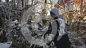 Man cyclist brushes his bicycle in the backyard in winter before taking it into the parking garage. Winter cycling and