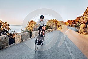 Man cyclist pedaling on a road bike outdoors in sun set