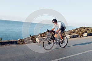 Man cyclist pedaling on a road bike outdoors in sun set