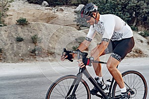 Man cyclist pedaling on a road bike outdoors in sun set