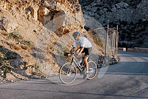 Man cyclist pedaling on a road bike outdoors in sun set