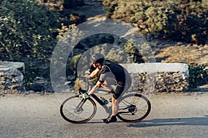 Man cyclist pedaling on a road bike outdoors in sun set