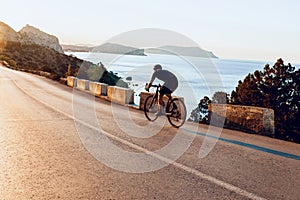 Man cyclist pedaling on a road bike outdoors in sun set