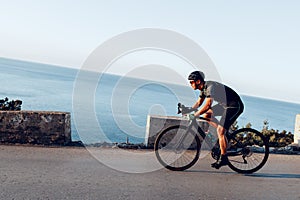 Man cyclist pedaling on a road bike outdoors in sun set