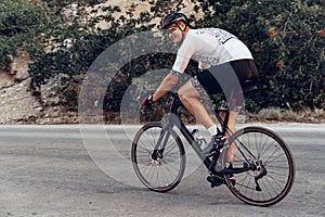 Man cyclist pedaling on a road bike outdoors in sun set