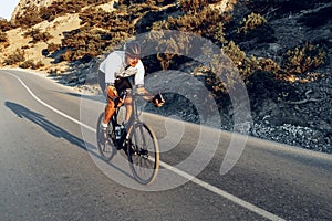 Man cyclist pedaling on a road bike outdoors in sun set