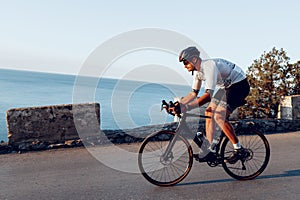 Man cyclist pedaling on a road bike outdoors in sun set