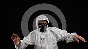 A man dances in a chemical protection suit with a respirator and goggles