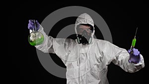 A man dances in a chemical protection suit with a respirator and goggles with a syringe and a flask