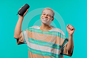 Man dancing, enjoying on blue studio background. Guy moves to rhythm of music. Young teenager listening to music by