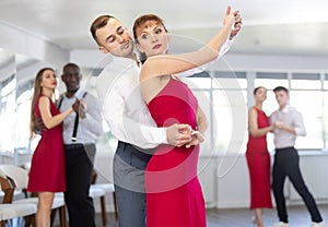 Man dancing merengue with woman in red in latin dance class