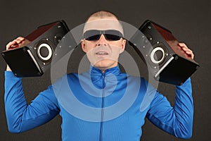 Man in dark glasses holding two powerful speakers