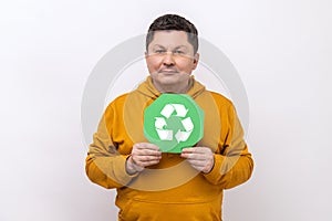 Man with dark hair showing green waste recycling symbol, satisfied with environmental safety.