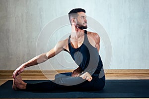 A man in dark sports clothes practicing yoga in a lotus position on a gray background. asana on the floor on yoga mats