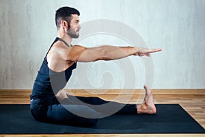 A man in dark sportswear practicing yoga on a dark background. asana on the floor on yoga mats. the concept of