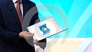 A man in a dark suit holds a opened folder with the image of the national flag of the Republic of Kazakhstan. The concept of award