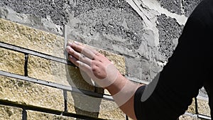 Man decorates the facade of a wall with decorative bricks, close up view. Process of cladding walls of constructions