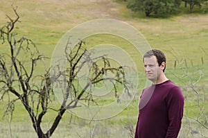 Man in deep thought outdoors in an open field.