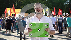 Man at a demonstrate with a placard. Green banner with points for tracking 4k.