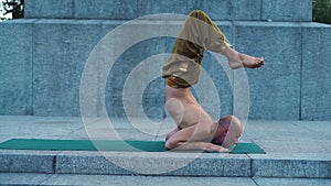 Man Demonstrates Flexibility of the Body Performing Asanas of Yoga in the City Park