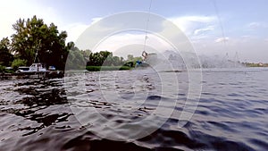 Man demonstrates sports tricks jumping on a wakeboard over the water.