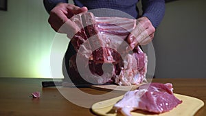 Man Demonstrating Meat, Pork Ribs. A Large Piece of Meat Lies on a Cutting Board beside Him. Home Kitchen, Cooking