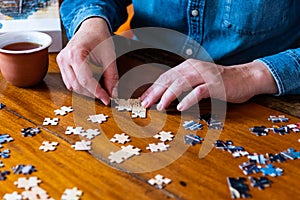 A man in denim shirt building a puzzle