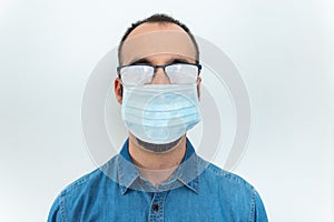 Man in denim shirt, face mask and misted glasses on white background