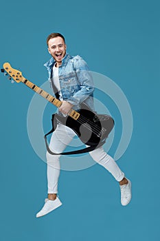 Man in denim t-shirt jeans with guitar jumping