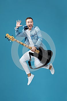 Man in denim t-shirt jeans with guitar jumping