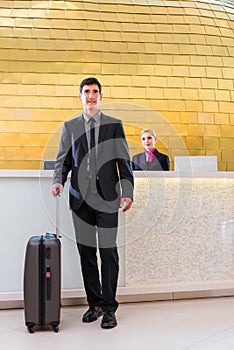 Man departing on business trip at hotel reception