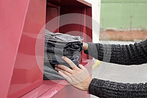 Man depositing used clothes in a clothing bin