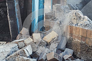 A man destroys a wall of old house. Dust and bricks in action