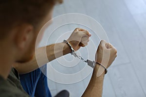 Man detained in handcuffs indoors, closeup view