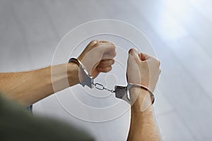 Man detained in handcuffs indoors, closeup view. Criminal