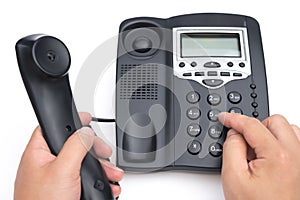 Man dialing a black telephone on white background