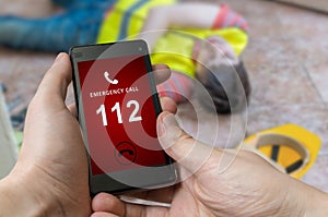 Man dialing emergency (112 number) on smartphone. Injured worker