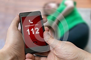 Man dialing emergency (112 number) on smartphone. Woman had hear