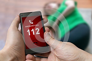 Man dialing emergency (112 number) on smartphone. Woman had hear photo
