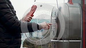 Man is dialing number on payphone