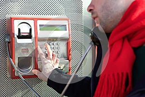 Man dialing phone number on public phone