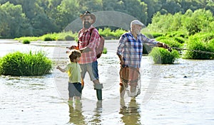 Man in different ages. Fishing. Grandpa and grandson are fly fishing on river. Man teaching kids how to fish in river.