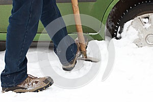 Man digging car wheels from snow