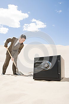 Man digging by safe in desert