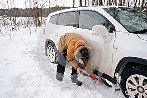 A man digs out a stalled car in the snow with a car shovel. Transport in winter got stuck in a snowdrift after a snowfall, sat on