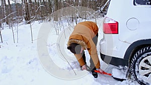 Man digs out stalled car in snow with car shovel. Transport in winter got stuck in a snowdrift after a snowfall, sat on bottom. Fi