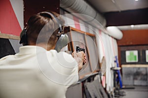 Man directs firearm gun pistol at target firing range or shooting range