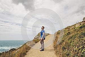 Man on a dirt road at the top of the hill looking up to the sky