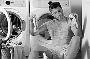Man with dirty laundry front of washing machine.