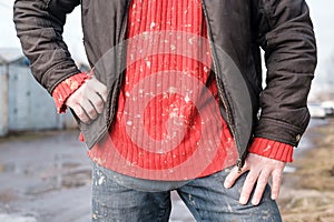 Man in dirty work clothes, a red knitted sweater and jeans.